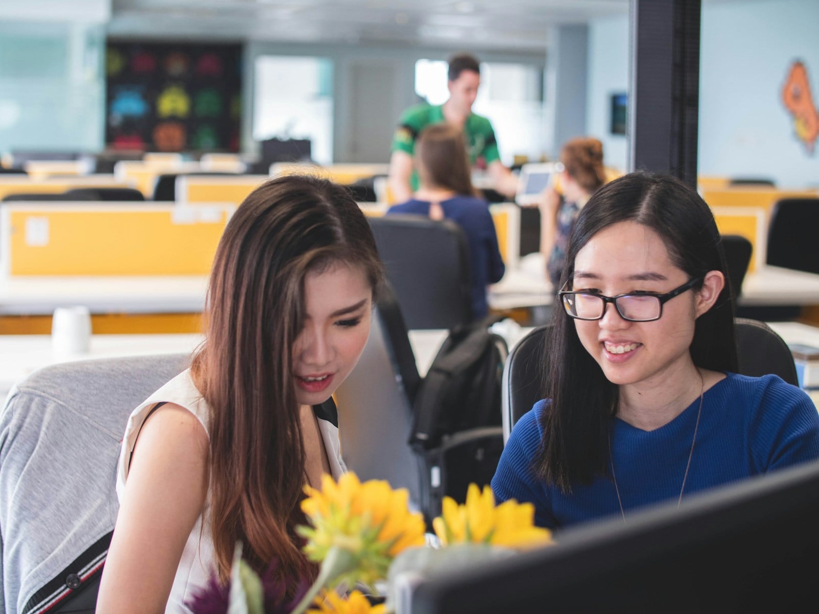 Asian colleagues reviewing Microsoft 365 security and compliance on a shared monitor