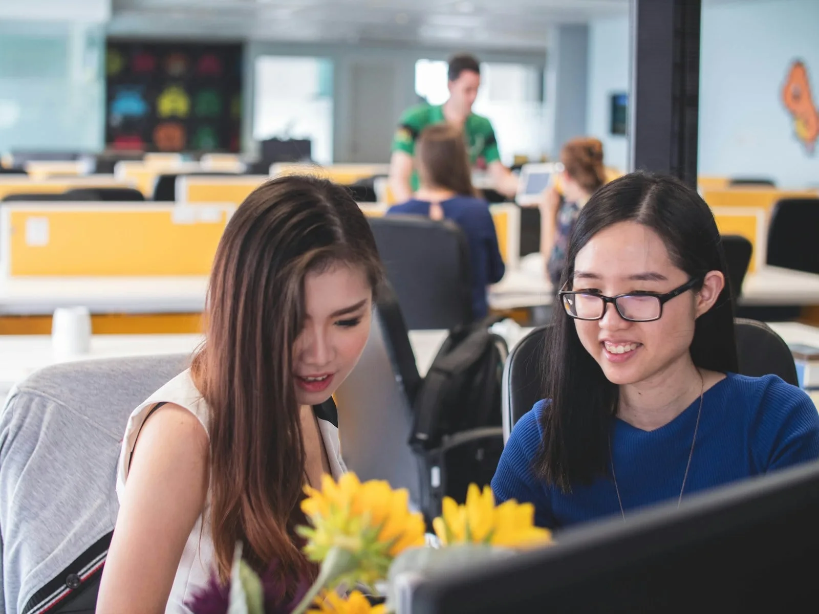 Asian colleagues reviewing Microsoft 365 security settings on a shared monitor